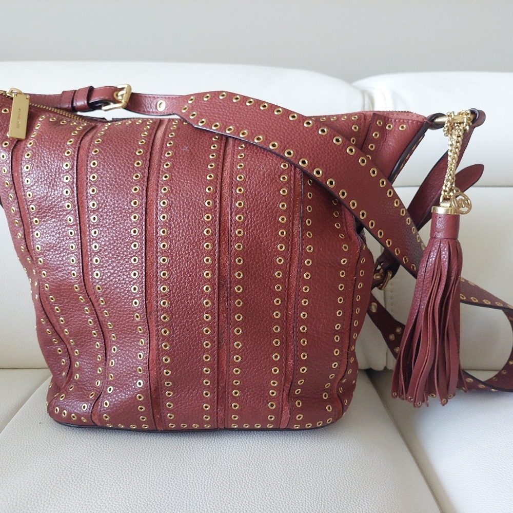 Michael Kors lether Brooklyn grommets a bag with a sholder strap. Brick color.